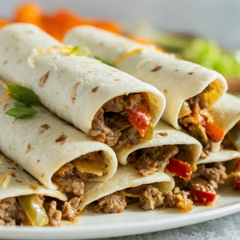 Stack of burrito-style wraps with ground meat and vegetables on a plate